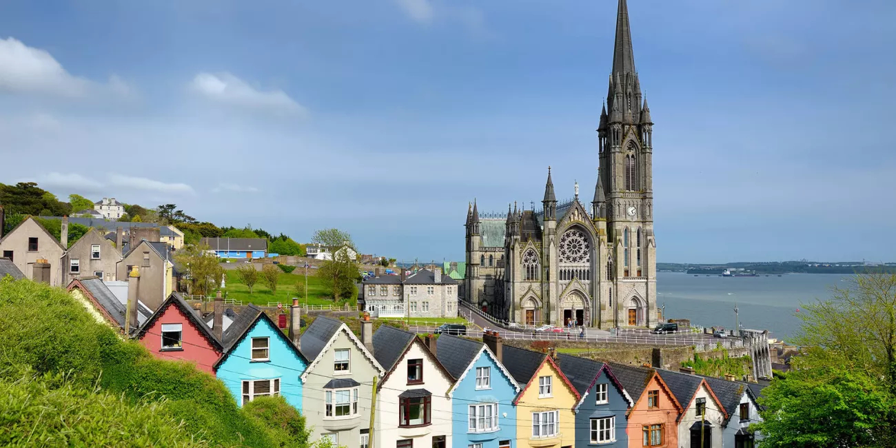 Colorful row houses with St. Colman's Cathedral in background in the port town of Cobh, County Cork, Ireland