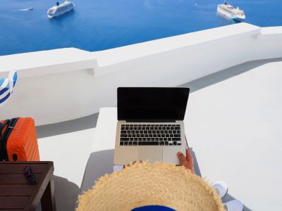 person in hat holding laptop enjoying the view 