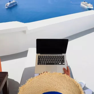person in hat holding laptop enjoying the view